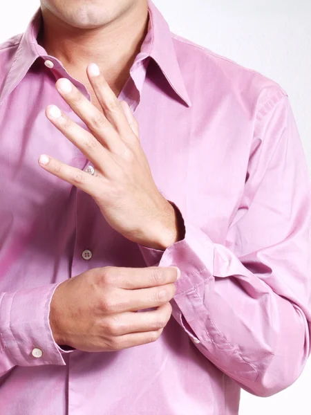 Jonge Spaanse man buttoning zijn shirt op witte achtergrond. — Stockfoto