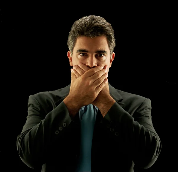 Podnikatel, pokrývající jeho ústa na černém pozadí. — Stock fotografie