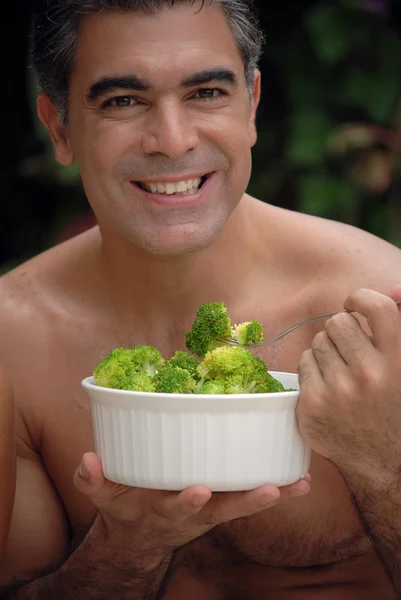 Jovem comendo legumes atrás de uma piscina . — Fotografia de Stock