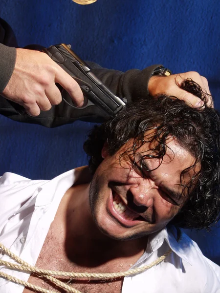 Desperate kidnapped man sitting in the room with the oversight of a gun to his head — Stock Photo, Image