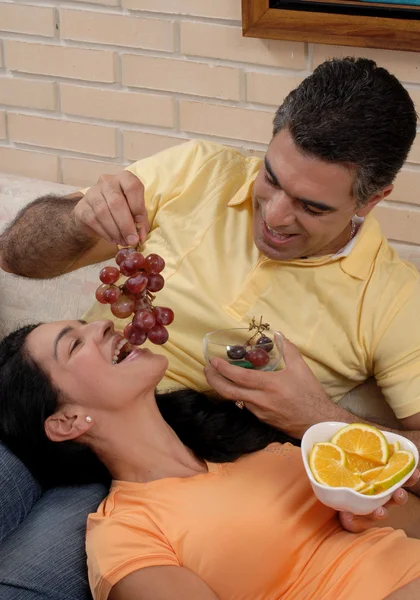 Mid adult couple eating fruits in a living room. — Stock Photo, Image