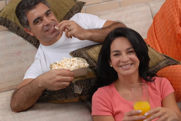 Casal assistindo TV e comendo pipocas. Compartilhamento de casais em uma sala de estar . — Fotografia de Stock