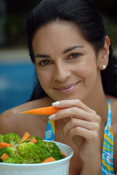 年轻女子在一个游泳池后面吃蔬菜. — 图库照片
