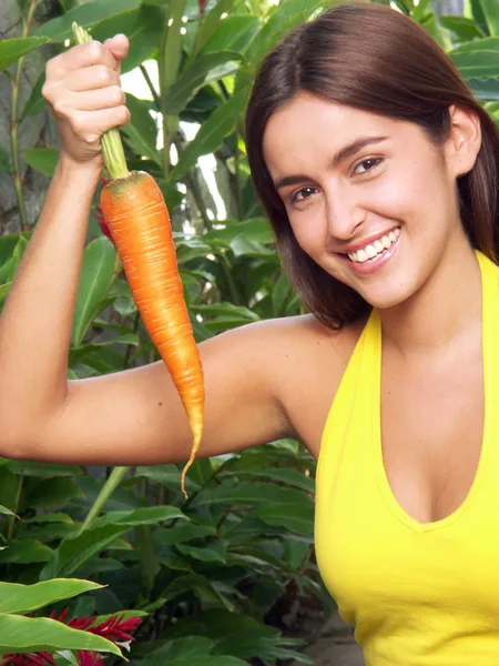 Mujer joven sosteniendo una zanahoria fresca . — Foto de Stock