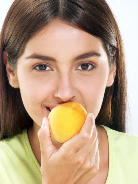 Молодая женщина ест персик — стоковое фото