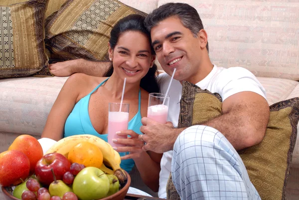 Mid adult couple drinking strawberry milkshake in a living room. — Stock Photo, Image