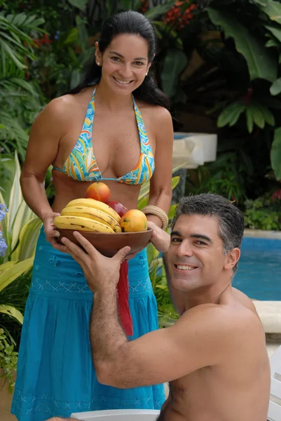 Coppia ispanica che mangia frutta tropicale in piscina . — Foto Stock