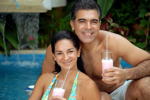 Lateinisches Paar trinkt Erdbeer-Milchshake im Schwimmbad. — Stockfoto