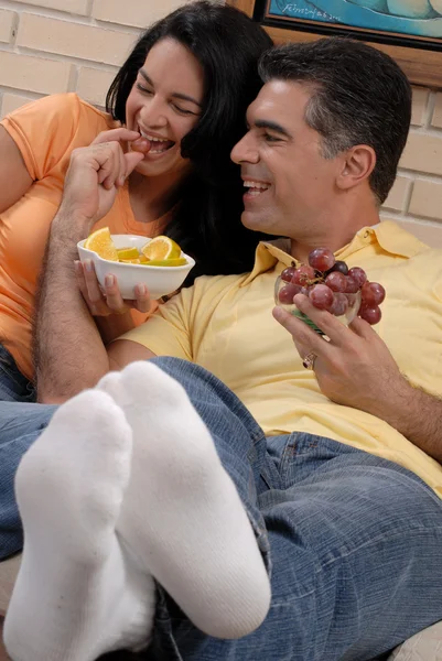 Mid adult couple eating fruits in a living room. — Stock Photo, Image