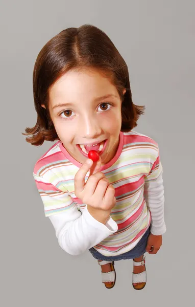 Klein meisje portret voorhanden hebben en het eten van snoep. — Stockfoto