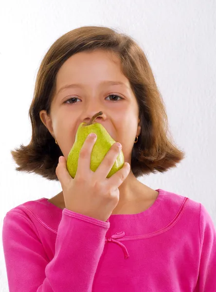Ragazzina che tiene e mangia pera fresca — Foto Stock