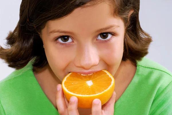 Menina segurando e comendo laranja — Fotografia de Stock