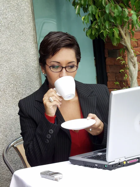 Mujer empresaria en un restaurante trabajando en una computadora . — Foto de Stock