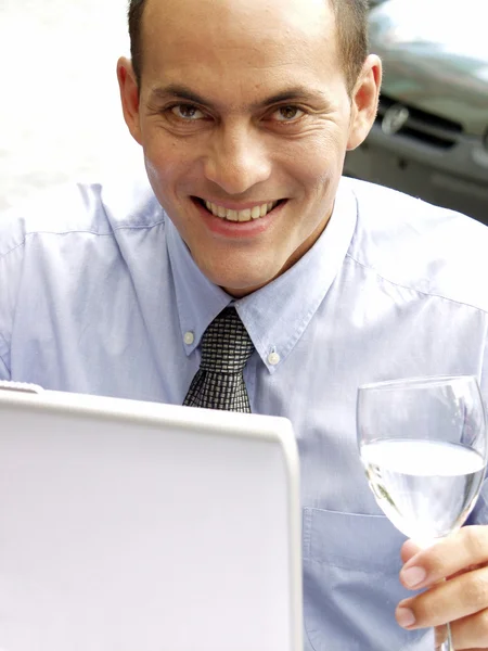 Jeune homme d'affaires travaillant avec un ordinateur portable tout en buvant de l'eau . — Photo