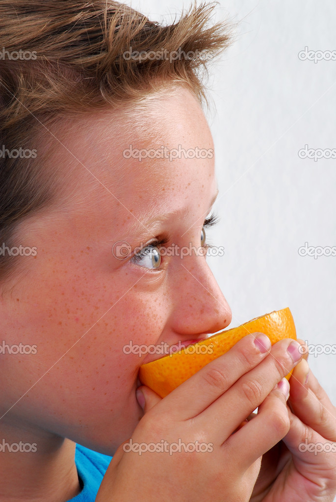 Little boy eating orange.