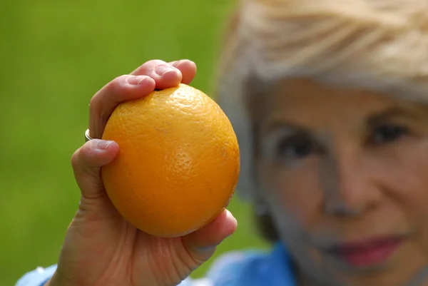 Взрослая женщина пьет апельсиновый сок. Взрослая женщина со свежими апельсинами . — стоковое фото