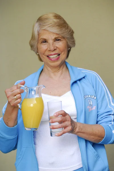 Середня доросла жінка п'є апельсиновий сік. Жінка тримає банку апельсинових соків . — стокове фото