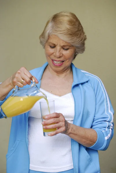 Mid adult woman drinking orange juice. Woman holding orange juice jar. — Stock Photo, Image