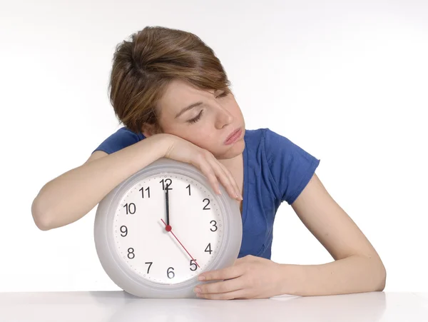 Junge Frau schläft über einer Uhr auf weißem Hintergrund. — Stockfoto