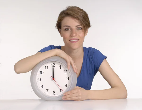 Junge Frau hält eine Uhr auf weißem Hintergrund. — Stockfoto