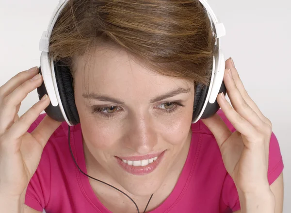 Müzik dinleme ve bir kulaklık tutan genç bir kadın. — Stok fotoğraf