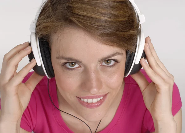 Mujer joven escuchando música y sosteniendo unos auriculares . —  Fotos de Stock