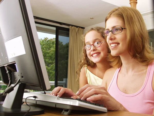 Jovem mãe e sua filha em um computador . — Fotografia de Stock