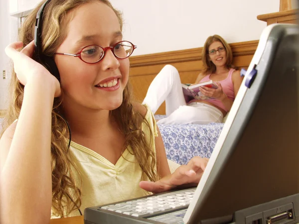 Jonge moeder en haar dochter op een computer. — Stockfoto