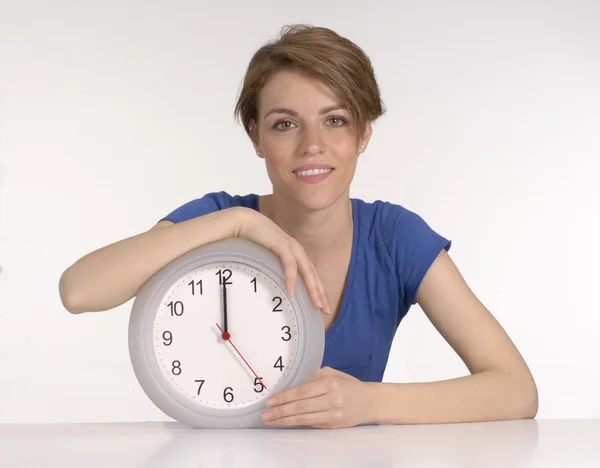 Young woman holding a clock on white background. Stock Photo