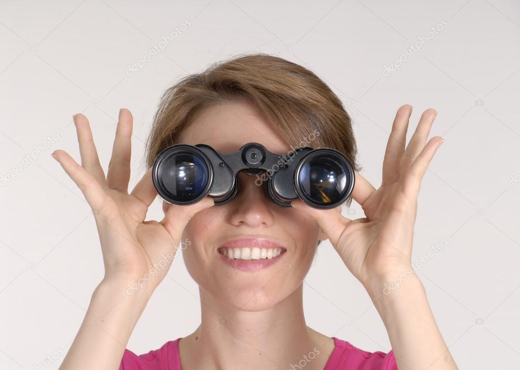 Young woman looking through binoculars.