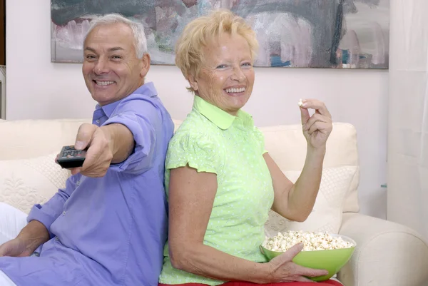 Gelukkige senior paar kijken televisie together.senior paar tv-kanalen wijzigen. — Stockfoto