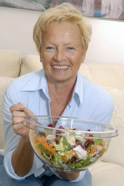 Senior vrouw een verse plantaardige salade eten op een kom. — Stockfoto