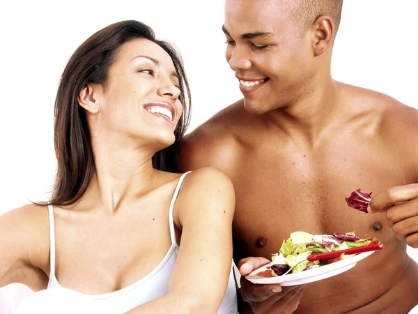 Joven pareja hispana disfrutando y comiendo ensalada de verduras sobre fondo blanco . — Foto de Stock