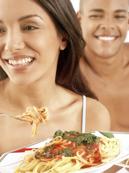 Unga spansktalande par njuter av och äta pasta på sängen. — Stockfoto
