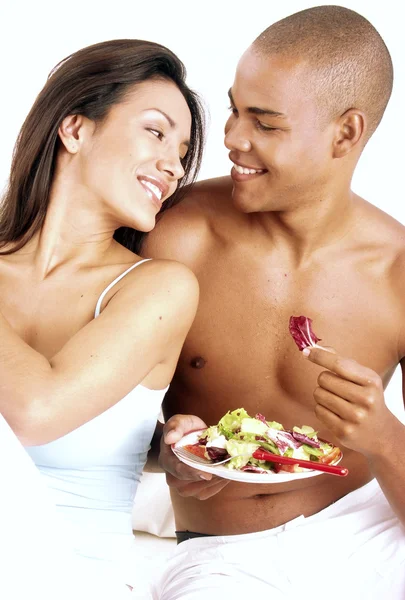 Young hispanic couple enjoying and eating vegetable salad on white background. — Stock Photo, Image