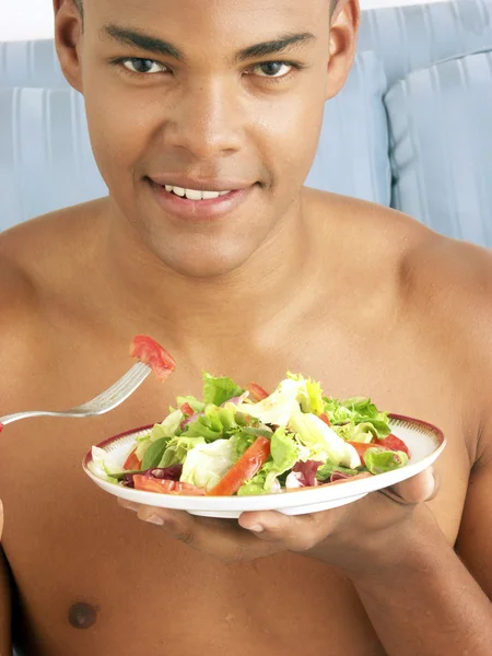Jonge Spaanse man eten plantaardige salade. — Stockfoto