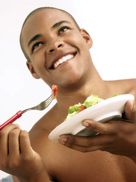 Jonge Spaanse man eten plantaardige salade. — Stockfoto