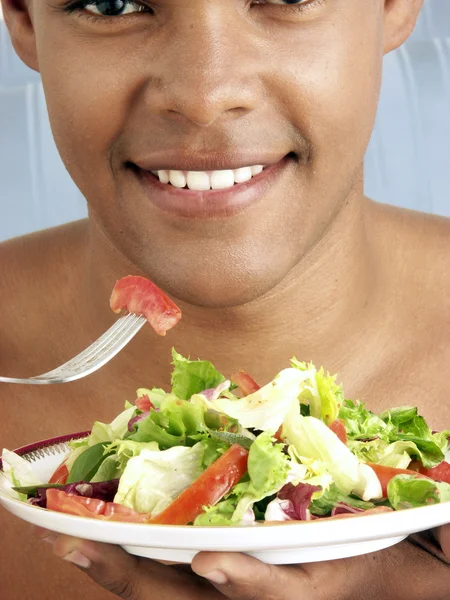 Jonge Spaanse man eten plantaardige salade. — Stockfoto