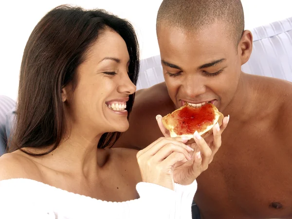 Hispanic young couple eating marmalade bread. — Stock Photo, Image