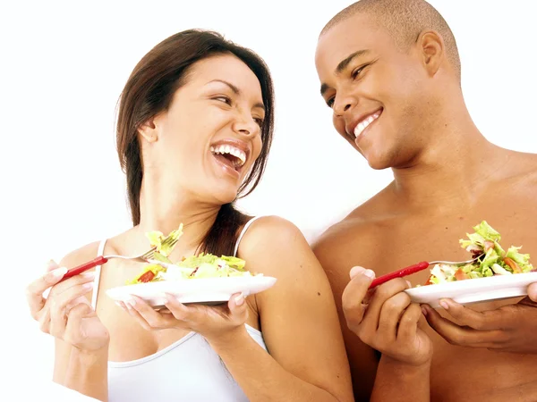 Joven pareja hispana disfrutando y comiendo ensalada de verduras sobre fondo blanco . — Foto de Stock