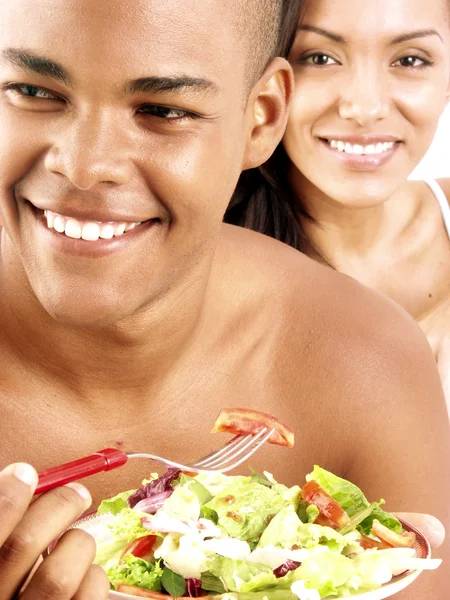 Joven pareja hispana disfrutando y comiendo ensalada de verduras sobre fondo blanco . — Foto de Stock