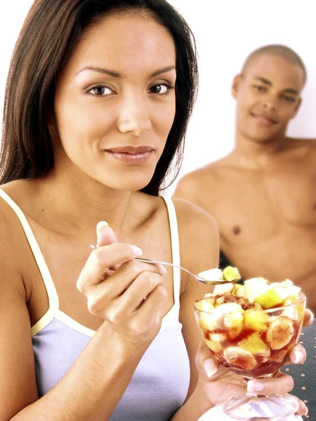 Jeune couple hispanique profiter et manger de la salade de fruits sur le lit . — Photo