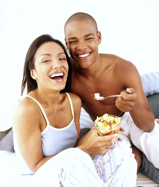 Genç İspanyol çiftin keyfi ve yatağın üstüne meyve salatası yemek. — Stok fotoğraf