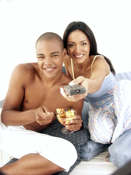 Giovane coppia ispanica godendo e mangiando macedonia di frutta sul letto . — Foto Stock