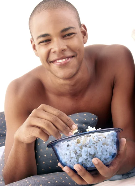 西班牙裔男子在床上吃爆米花. — 图库照片