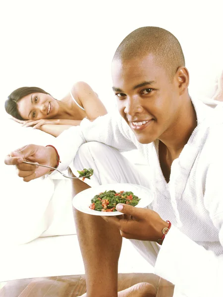 西班牙裔美国人的年轻夫妇享受和在床上吃意大利面. — 图库照片