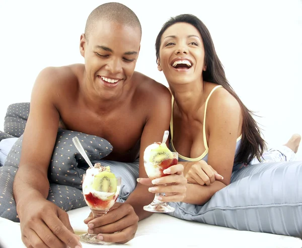 Young hispanic couple enjoying and eating fruit salad on bed. — Stock Photo, Image