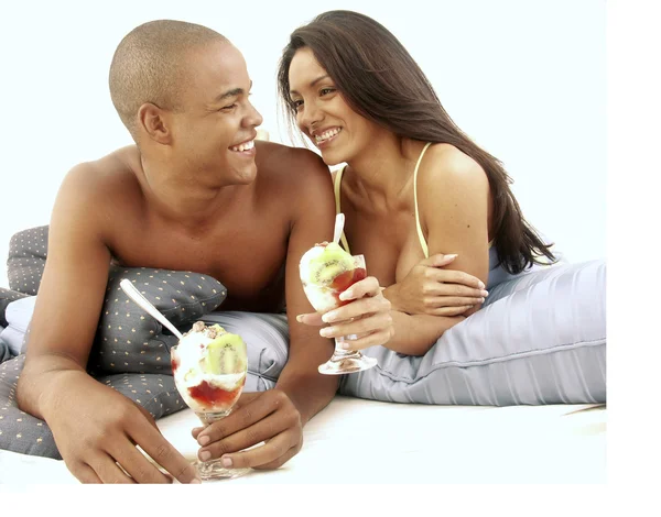 Young hispanic couple enjoying and eating fruit salad on bed. — Stock Photo, Image