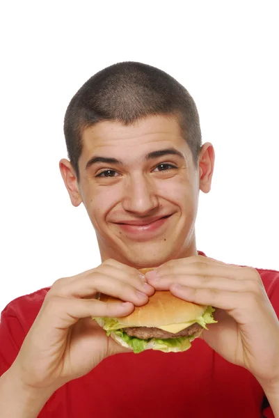 Jovem segurando e comendo um hambúrguer no fundo branco . — Fotografia de Stock