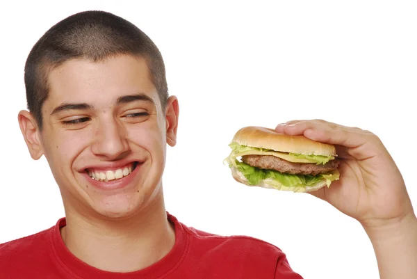 Mladý kluk, držení a jíst hamburger na bílém pozadí. — Stock fotografie